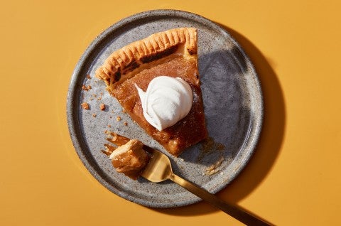 A slice of Maple Cream Pie on a plate topped with whipped cream with a bite on a fork - select to zoom