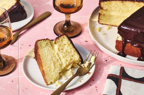 A slice of Boston Cream Pie on a plate with a fork and bite taken out of it.