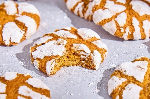 Pumpkin Crinkle Cookies on parchment paper; one with a bite taken - select to zoom