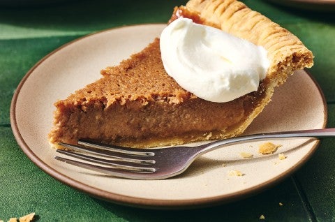 Slice of smooth boiled apple cider pie shown from the side and topped with a dollop of whipped cream. - select to zoom