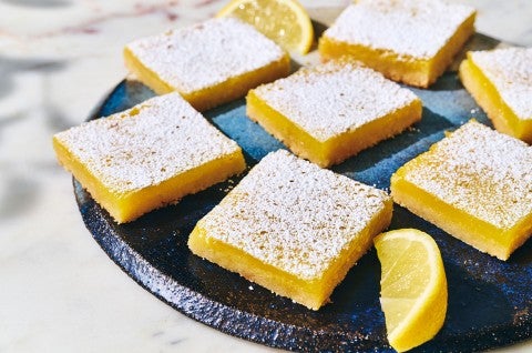 Gluten-Free Lemon Squares with an Almond Flour Crust on a dark plate with a slice of lemon as garnish. - select to zoom