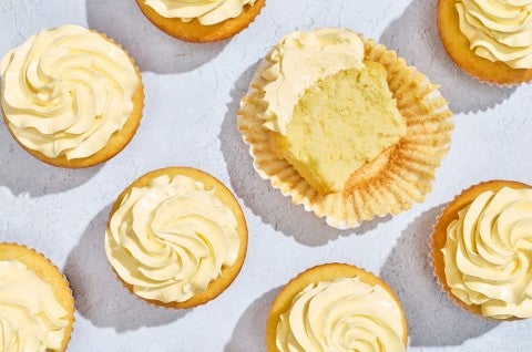 Cupcakes seen from above with French Buttercream as the frosting. One cupcake is sliced in half and laying on its side. - select to zoom