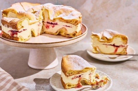 Karpatka Cake on a cake stand with slices on plates. - select to zoom