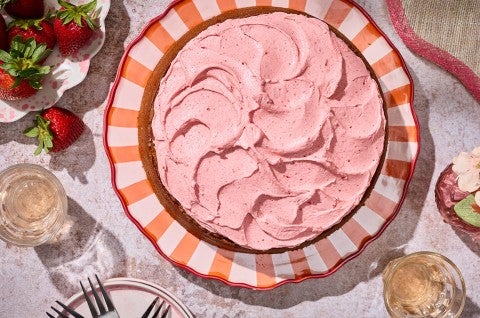 Brown Sugar Strawberry Frosted Cake on a table atop a striped plate - select to zoom