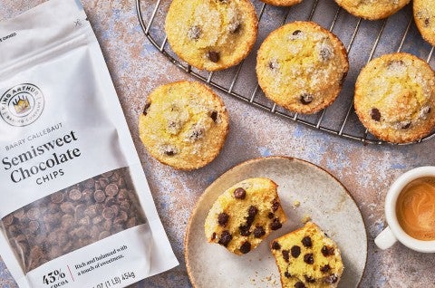 Easy Chocolate Chip Muffins on a plate and a cooling rack with a bag of Semisweet Chocolate chips from King Arthur Baking - select to zoom