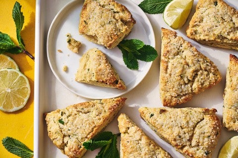 Mojito Scones on a plate and a platter with limes and mint leaves decorating the photo. - select to zoom