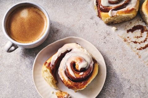 A Sourdough Cinnamon Roll on a plate accompanied by coffee - seen from above. - select to zoom