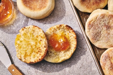 A Sourdough English Muffin sliced on a counter with butter on one half and jam on the other - select to zoom
