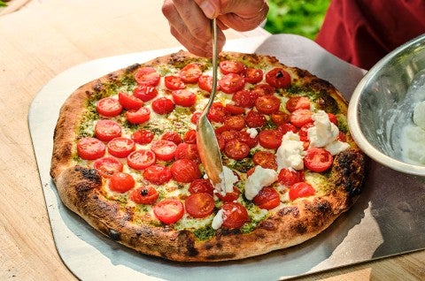 Adding fresh mozzarella to caprese style NY pizza fresh out of the oven - select to zoom