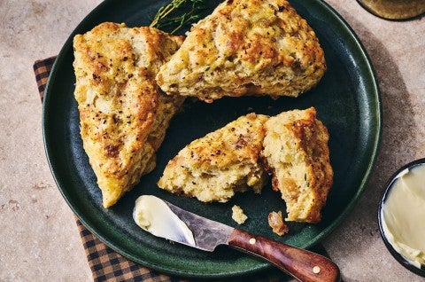 French Onion Scones on a dark plate with a butterknife - select to zoom