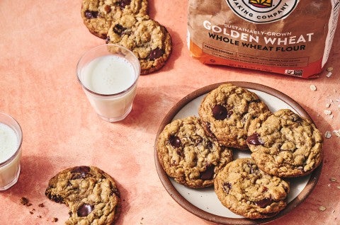 Whole Wheat Oatmeal Cookies on a plate with a glass of milk and a cookie with a bite taken out on a counter seen from above - select to zoom