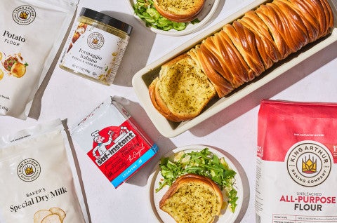 Butterflake Herb Loaf in a pan showing the buttery and herbaceous interior surrounded by the ingredients to bake it - select to zoom