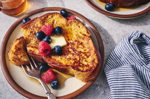French toast on a plate with fresh berries and butter. - select to zoom