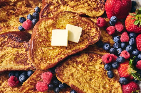 French Toast stacked together with pats of butter and surrounded by fresh berries - select to zoom