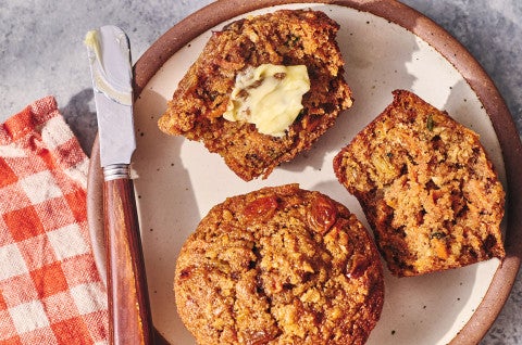 Morning Glory Muffins seen from above on a plate. One is split with butter on it. - select to zoom