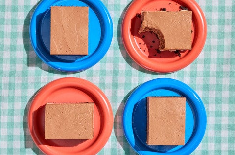 Four slices of No-Bake Chocolate Cheesecake Bars on a table on blue and red plates - select to zoom