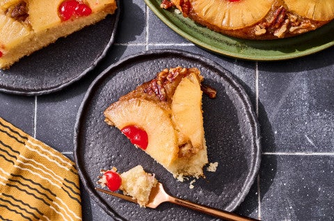A slice of Pineapple Upside Down Cake on a plate with a bite on a fork seen from above. - select to zoom