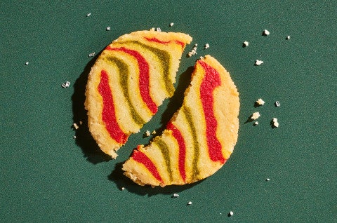 A broken Ribboned Peppermint Shortbread Cookie on a green background - select to zoom