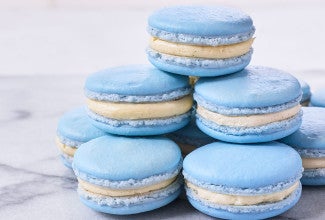 A stack of blueberry macarons on a marble countertop.