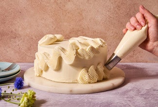 frosting being piped on a frosted cake