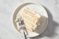 A single slice of Coconut Layer Cake on a plate with a fork