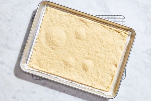 Parbaked Gluten-Free pizza dough in a rectangular sheet pan seen from above.