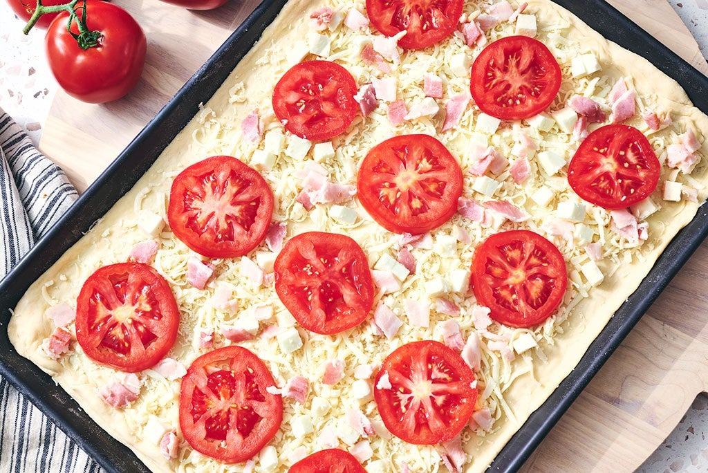 BLT Pizza before baking with tomatoes and bacon and cheese on the dough