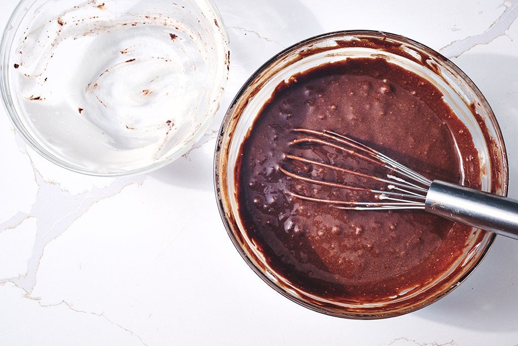 Mixing and whipping chocolate and meringue in bowls to make flourless chocolate lava cake