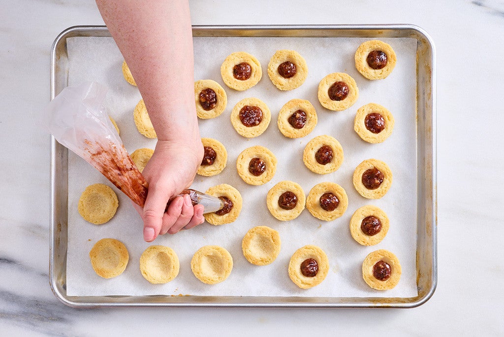 Filling halves of Sugar Plum Cookies on a baking sheet