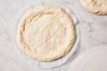 Shaped round of unbaked pizza dough