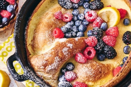 Lemon Puff Pancake with Fresh Berries in a cast iron pan topped with powdered sugar and berries