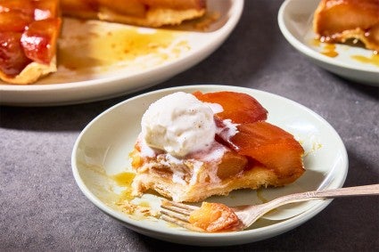 A slice of Classic Apple Tarte Tatin on a plate with a scoop of vanilla ice cream on top