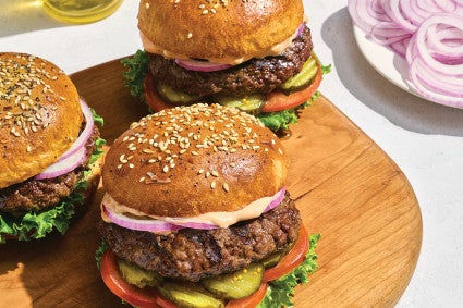 Hamburgers in Whole Wheat Hamburger Buns on a cutting board.