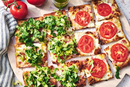 BLT Pizza with half covered with freshly chopped lettuce