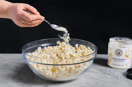 Better Cheddar Cheese Powder being sprinkled over popcorn