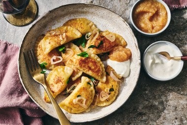 Homemade Pierogis on a plate with perfectly browned exteriors, garnished with herbs and onions.