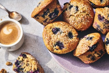 Sourdough Discard Blueberry Muffins on a counter with a cup of coffee in the frame.