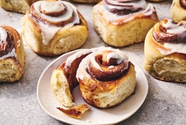 A Sourdough Cinnamon Roll on a plate accompanied by coffee.