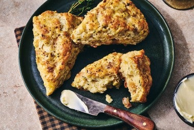 French Onion Scones on a dark plate with a butterknife