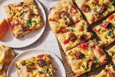 Sliced breakfast pizza on a cutting board with some slices on plates