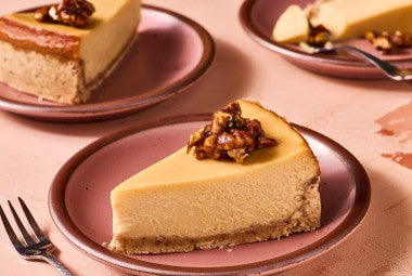 A slice of Maple Pecan Cheesecake on a pink plate, seen from the side