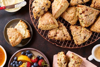 Scones on a cooling rack and plates with fresh fruit